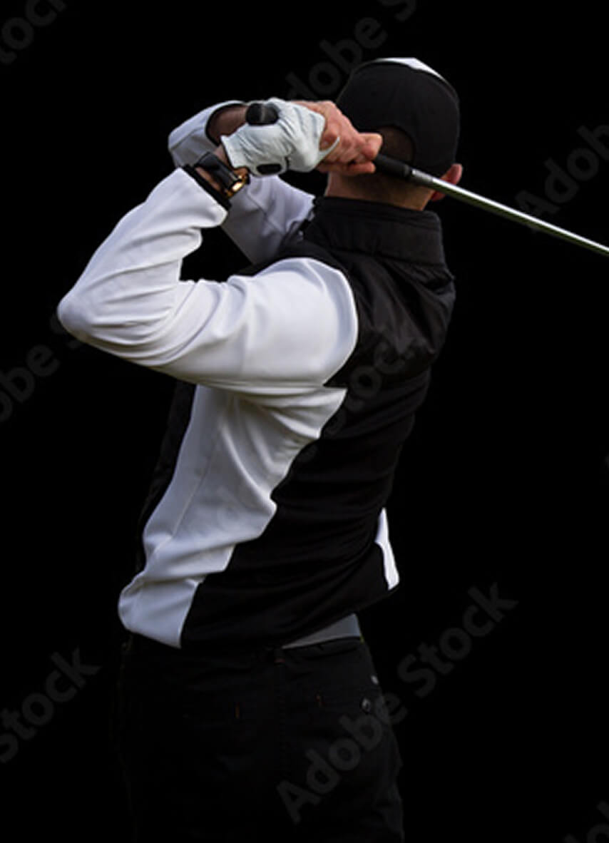 Person in black and white outfit swinging a golf club against a black background